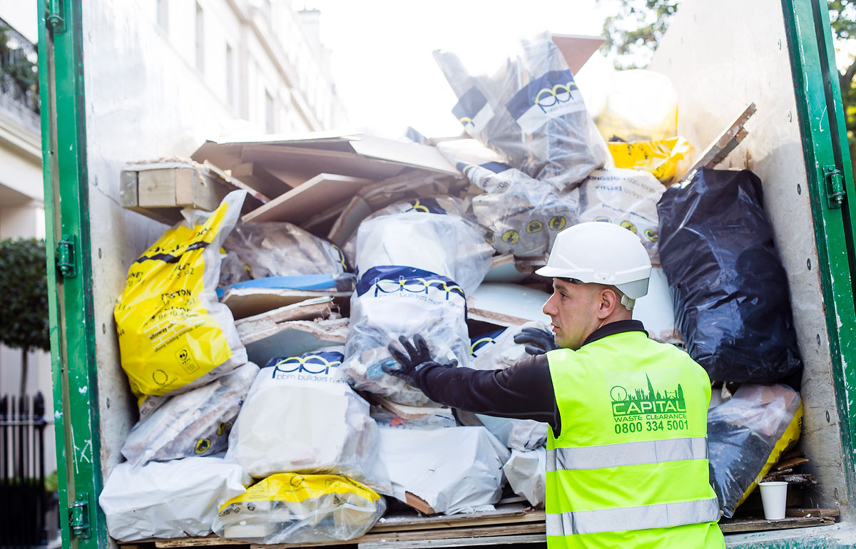 Capital Waste Clearance team member loading a rubbish truck on a London street