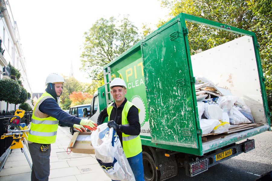 Two Capital Waste Clearance workers smiling by branded truck on a London street